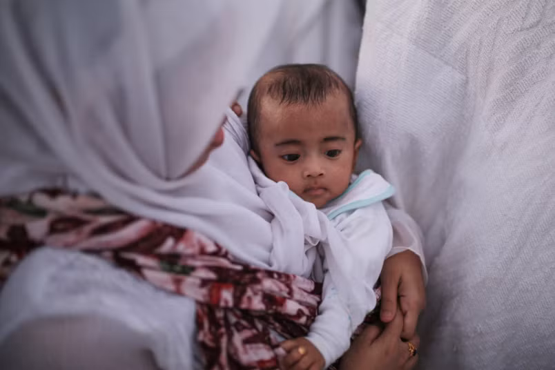 Một người hành hương bế con nhỏ trong lúc cầu nguyện.