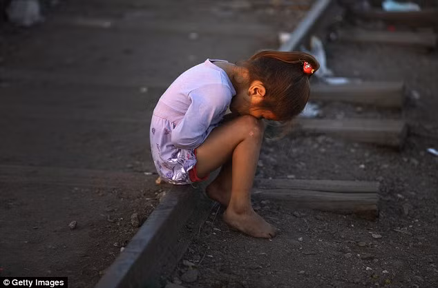 Một bé gái Syria ngồi trên đường ra tàu tại biên giới Serbia – Hungary cùng gia đình chờ đến khi trời tối để vượt biên.