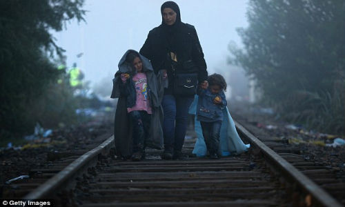 Ba mẹ con dắt tay nhau đi bộ trên đường tàu khi tới biên giới Hungary – Serbia. Hành trình tới “miền đất hứa” còn lắm gian nan giữa cuộc khủng hoảng tị nạn.