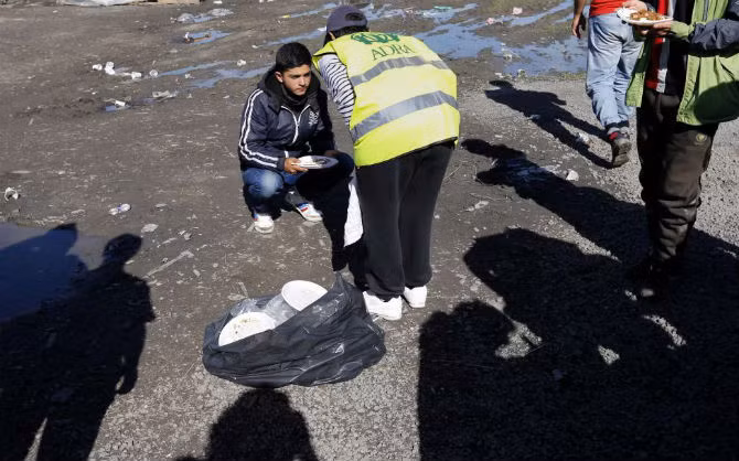 Thành viên của tổ chức cứu trợ trò chuyện với một di dân tại khu trại dành cho người tị nạn ngày 20/9.