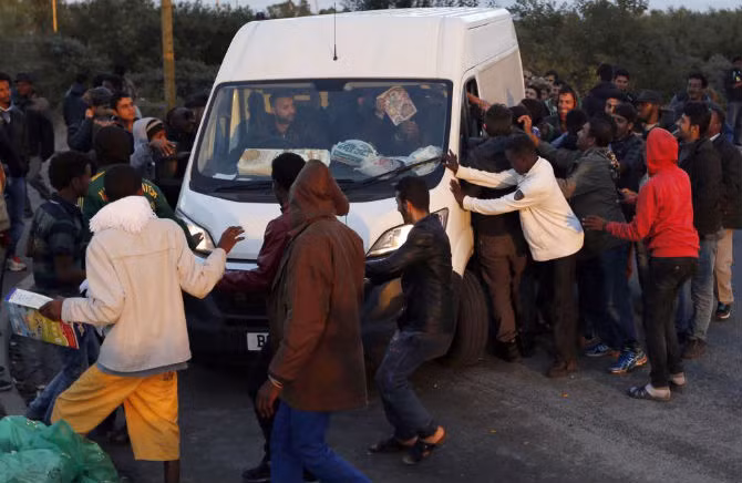 Những người tị nạn vây quanh một chiếc xe tải chở các thành viên của một tổ chức cứu trợ đến phân phát thực phẩm cho người tị nạn ở khu trại New Jungle ở Calais ngày 18/9.