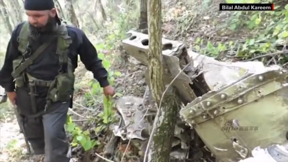 Chiến binh phiến quân đứng cạnh đống đổ nát máy bay ném bom Su-24 Nga.