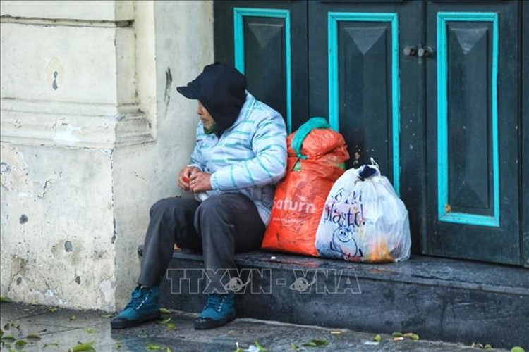 Một người lang thang co ro trong giá rét trên phố Đinh Tiên Hoàng. Trời trở rét kèm theo mưa nhỏ, người đi đường đã cảm nhận được cái lạnh tê tái. (Ảnh: TTXVN).