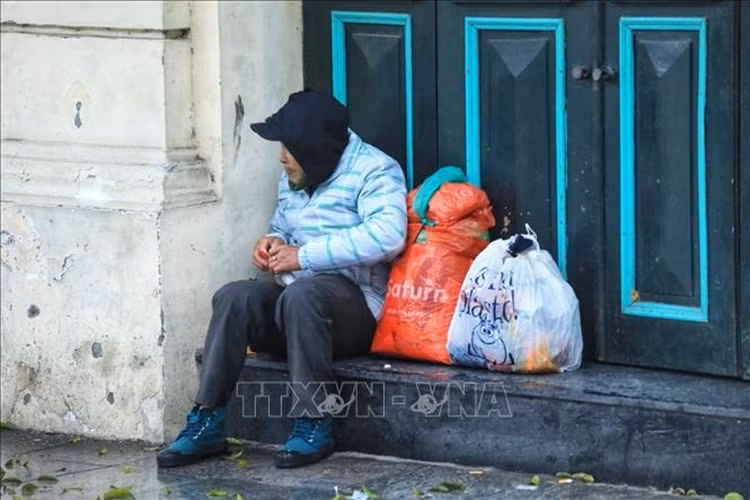 Một người lang thang co ro trong giá rét trên phố Đinh Tiên Hoàng. Trời trở rét kèm theo mưa nhỏ, người đi đường đã cảm nhận được cái lạnh tê tái. (Ảnh: TTXVN).