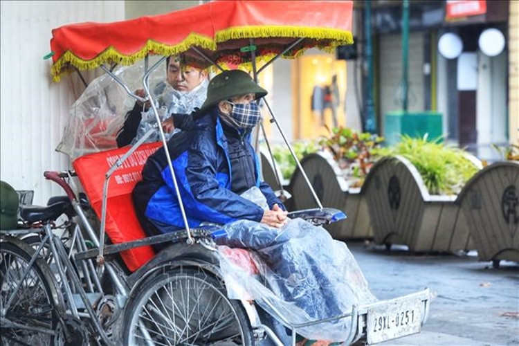 Một người đạp xích lô du lịch chờ khách co ro trong giá rét trên phố Đinh Tiên Hoàng. (Ảnh: TTXVN).