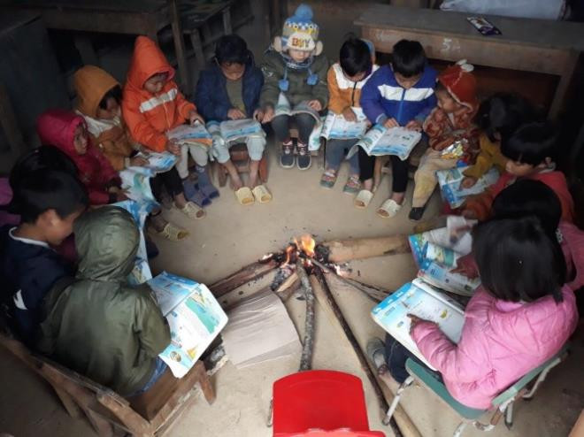 Học sinh tại điểm trường Y Tý (huyện Bát Xát, tỉnh Lào Cai) quây quần bên đống lửa sưởi ấm trong cái lạnh 4 độ C. Giáo viên tại điểm trường cho biết phải thường xuyên đốt củi trước và trong giờ học để sưởi ấm cho học sinh. (Ảnh: GVCC) 