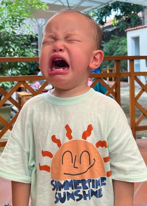 Cậu nhóc nhắm tịt mắt, miệng há to khi khóc.