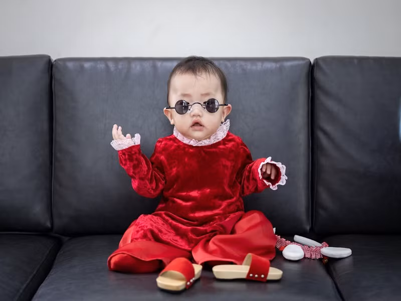 Bé Vừng được mẹ cho mặc áo dài, đeo kính đen, đi guốc mộc.