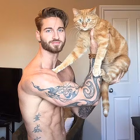 Travis DesLaurier (Canada) vốn là người mẫu, sở hữu ngoại hình điển trai cùng cơ thể 6 múi quyến rũ, nhưng được biết đến nhiều hơn sau khi anh đăng clip tập thể dục cùng thú cưng - chú mèo Jacob lên mạng xã hội. Đoạn video thu hút hơn 11 triệu lượt xem chỉ trong 2 ngày. Ảnh: Instagram NV.