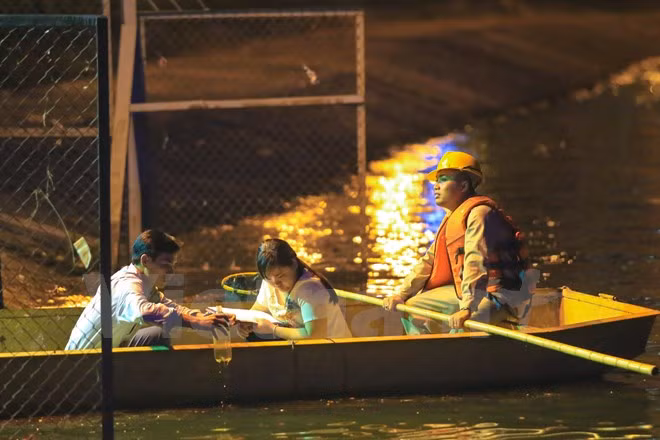 Cơ quan chức năng xuống hiện trường hồ Hoàng Cầu lấy mẫu nước để kiểm tra. (Ảnh: Minh Sơn/Vietnam+)