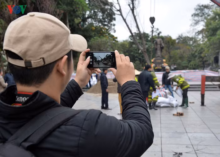 Một vài người dân ghi lại khoảnh khắc những cây anh đào đầu tiên được dựng tại vườn hoa Lý Thái Tổ.