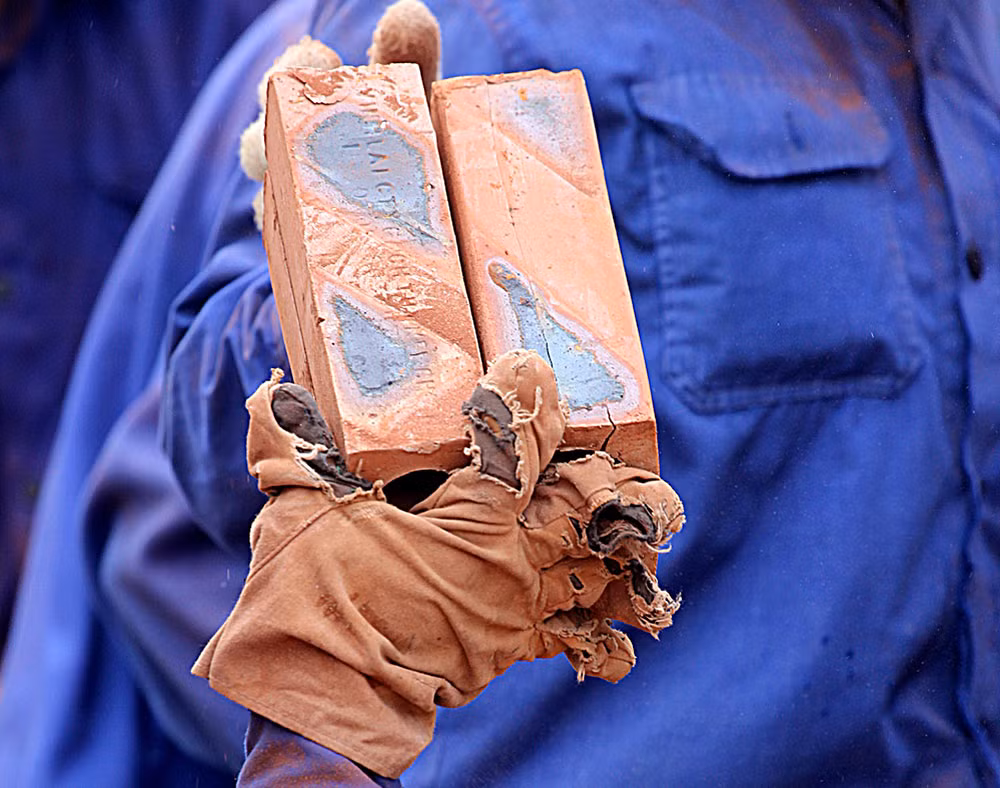 Găng tay dày vẫn bị bục nát do tiếp xúc liên tục với những viên gạch đã ra lò sắc cạnh