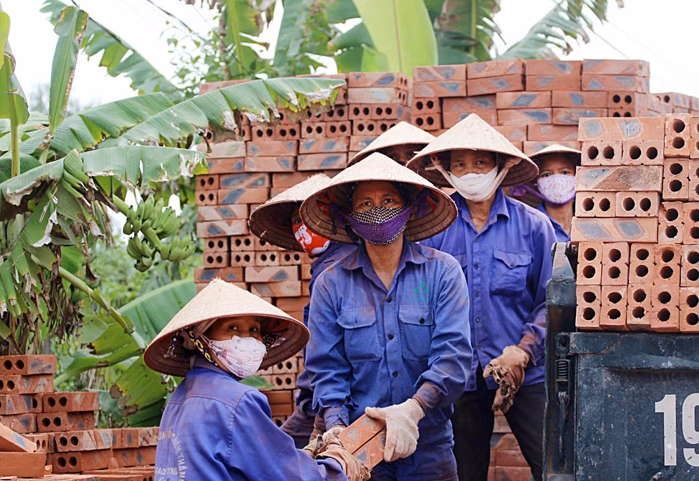 Nhóm công nhân vận chuyển gạch thành phẩm chất lên xe tải trong điều kiện nắng nóng.