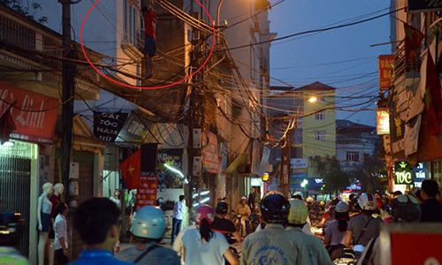 Nam thanh niên mặc áo phông đỏ đu trên dây cáp giữa đường Khương Đình. Ảnh: Quân Nguyễn.