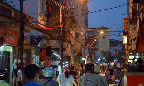 Nam thanh niên mặc áo phông đỏ đu trên dây cáp giữa đường Khương Đình. Ảnh: Quân Nguyễn.