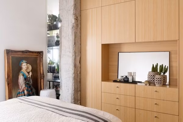 Phòng ngủ được bố trí hệ thống tủ âm tường đối diện với giường ngủ. Tủ có nhiều ngăn với diện tích khác nhau, phù hợp để đặt được vô số đồ đạc bên trong gọn gàng, ngay ngắn. Khoảng giữa của tủ được bố trí thêm gương, tạo bàn trang điểm xinh xắn, tiện lợi.