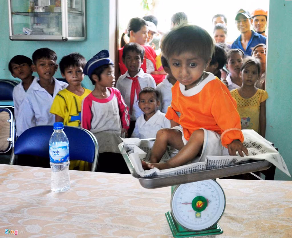 Nhiều đứa trẻ ở xã Sơn Ba tò mò khi nhìn các y, bác sĩ cân trọng lượng kiểm tra sức khỏe cho bé K''Rể. Ông Đinh Văn An (cha K’Rể), cho biết, lúc chào đời, con trai chỉ bằng gang tay, dân làng cho là "điềm xấu" ai cũng sợ bảo mang ra bìa rừng chôn. Vợ chồng tôi nài nỉ mãi, dần dần dân làng hiểu ra mới để nuôi cháu đến ngày nay.