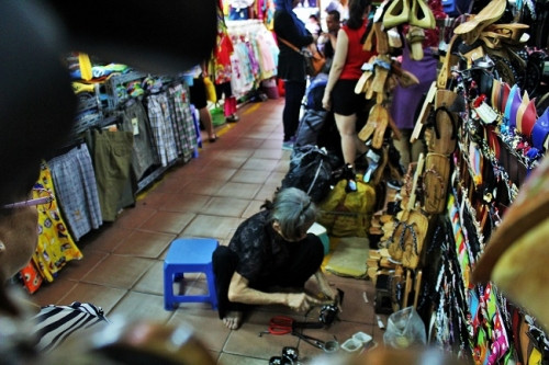 Cứ thế, suốt hơn nửa thế kỷ qua cứ đúng 10 giờ lại thấy bà lão đầu bạc trắng, dáng người nhỏ nhắn lúc nào cũng lom khom sắp xếp những đôi guốc ngay ngắn rồi lại ngồi nhìn dòng nười tấp nập bên cửa Tây của chợ Bến Thành. Ảnh: Ngọc Nhiên