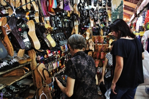 Có 2 vị khách tìm đến để đóng guốc, bà lão mừng rỡ, nhiệt tình tư vấn cho 2 vị khách. Do bà lão đang bận nên tôi không dám làm phiền, đứng một góc để quan sát cách bà chọn những đế, thân guốc và dùng những dụng cụ hành nghề để cho ra một đôi guốc theo đúng yêu cầu của khách. Đợi khi bà lão hết khách, tôi mới dám lại hỏi thăm nhưng bà lại không đồng ý thế nên tôi lại phải đứng nép qua một bên vì sợ làm phiền bà. Một hồi lâu sau, bà thấy tôi vẫn đứng đó rồi lấy cái ghế nhựa nhỏ bảo tôi: ‘ngồi đi, cô muốn hỏi gì thì hỏi đi, tôi trả lời cô thấy cô đợi tôi nãy giờ’.