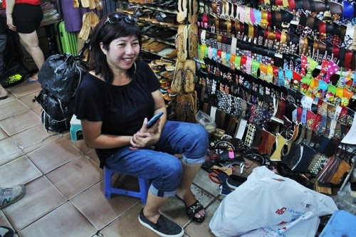 Một người khách quen tìm đến sạp của bà Liên để mua những đôi guốc về cho con cháu. Ảnh: Ngọc Nhiên