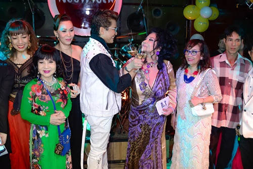 Cả hai vợ chồng cùng nhau cắt bánh giữa sự chứng kiến của bạn bè.