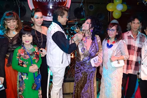 Cả hai vợ chồng cùng nhau cắt bánh giữa sự chứng kiến của bạn bè.