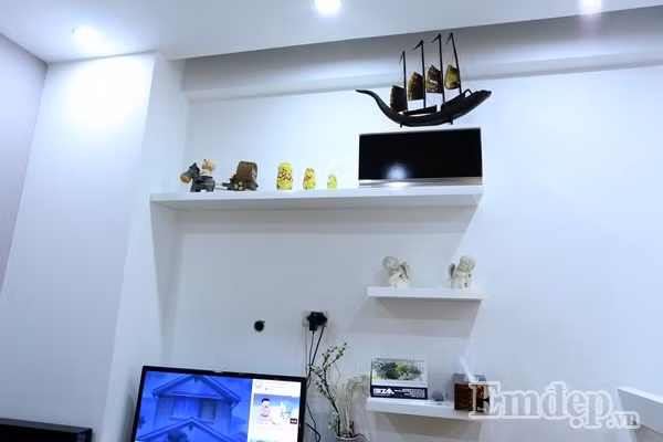 Kệ để đồ cùng tông trắng với màu tường, tạo cảm giác rộng và thoáng hơn cho không gian phòng khách. Bên trên bài trí các vật trang trí xinh xắn, theo sở thích của các thành viên trong gia đình.