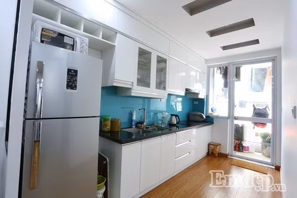 Hệ thống tủ giấu tường trên cao và kệ bếp phát huy tối đa công năng sử dụng khi đảm bảo mọi tiện nghi được triển khai trong không gian nhỏ gọn nhất. Bên ngoài cửa bếp là ban công rộng chưa đến 5m2, được gia chủ tận dụng để phơi áo quần.