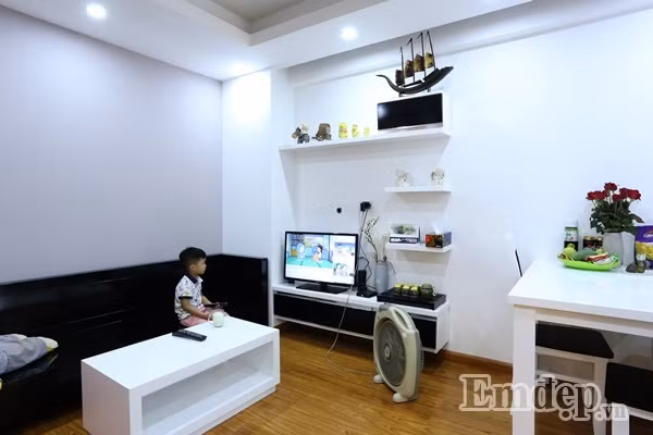 Không gian phòng khách được bài trí đơn giản với bàn cà phê, ghế sofa đơn sát tường, kệ để đồ và ti vi.