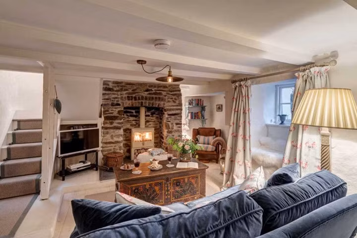 Bên trong nhà, phòng khách có nội thất hiện đại với ghế mềm mại và ấm cúng, TV, lò sưởi và góc đọc sách.