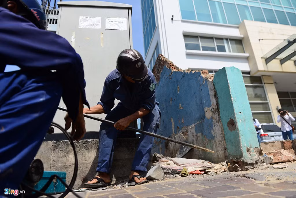 Công nhân gấp rút phá dỡ bức tường, trả lại vỉa hè cho người đi bộ.