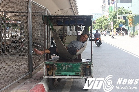 Những tài xế xe ba gác đang dựa vào bóng mát dưới chân cầu vượt để ngủ. Chiếc xe được trang bị sẵn võng phía sau để phục vụ giấc ngủ giữa trưa hè nắng nóng.