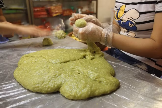 Người thợ làm bánh thuần thục chia nhỏ từng phần bánh cùng với nhân đỗ đã chia phần.