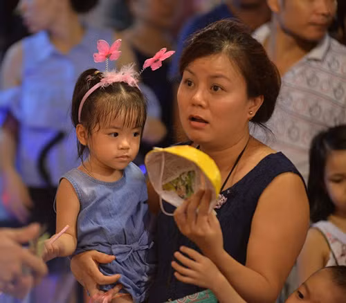 Một phụ huynh đang chọn mua một chiếc mặt nạ giấy cho cô con gái nhỏ.