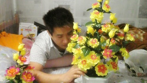 Tuấn bên sản phẩm hoa nhựa của vợ.