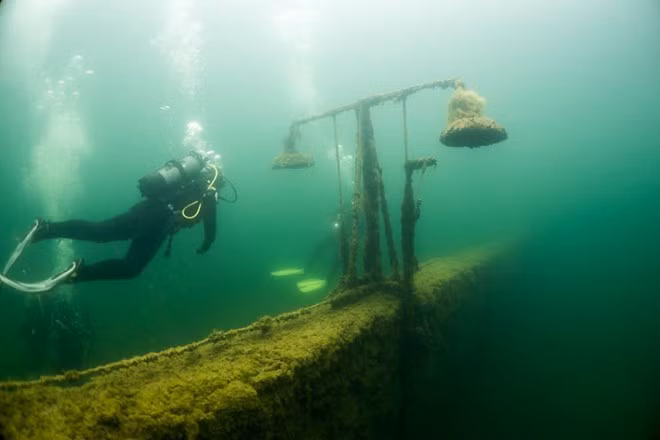 Nhóm thợ lặn ưa thích nơi này hơn cả. Họ phải lặn xuống dưới nhà sàn, bơi sâu vào bên trong. Một việc làm khá nguy hiểm vì vẫn còn những hàng rào dây thép gai cũ, tấm bê tông ngổn ngang sót lại. Rong rêu bám đầy xung quanh và còn nhiều vật dụng cũ chìm sâu dưới nước. Độ sâu ở đây ít nhất lên tới 13 mét nhưng các thợ lặn chỉ xuống ở mức 6-9 mét.