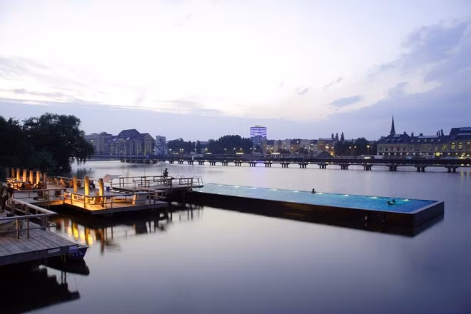 Bể bơi Badeschiff, Berlin, Đức: Bể bơi độc đáo này là một điểm đến đông khách vào mùa hè, nằm trên sông Spree xinh đẹp. Bạn có thể ngâm mình trong nước, thưởng thức cocktail trong ánh hoàng hôn, hay ngắm nhìn cây cầu Oberbaumbrücke. Vào mùa đông, Badeschiff được lợp mái che và biến thành quán rượu kiêm xông hơi. Ảnh: Arena.berlin.