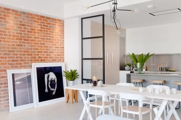 Không gian ăn uống Từ khu vực lối vào nhà là không gian dành cho chức năng ăn uống hàng ngày của gia đình. Chỉ với bộ bàn ghế ăn đơn giản với sự kết hợp hài hòa giữa chất liệu kim loại làm chân bàn chắc chắn và gỗ màu sáng làm mặt bàn giúp cho góc ăn uống luôn đẹp giản dị. Những gam màu sáng của bộ bàn ghế ăn giúp cho không gian ăn uống trở nên dễ nhìn và cũng giúp căn hộ đẹp thoáng sáng hơn. Sàn nhà cùng với một phần của tường được chọn lựa gam màu sáng tương đồng với nội thất, giúp bức tường bằng gạch trần đẹp nổi bật và tinh tế.