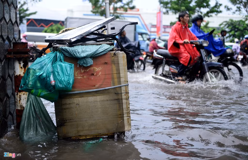 Đồ đạc của người bán hàng rong đầu đường Tiền Giang, đoạn giao với Trường Sơn bị ngâm trong nước. Nhiều người vội vàng vượt qua đoạn đường ngập nước để kịp vào sân bay.