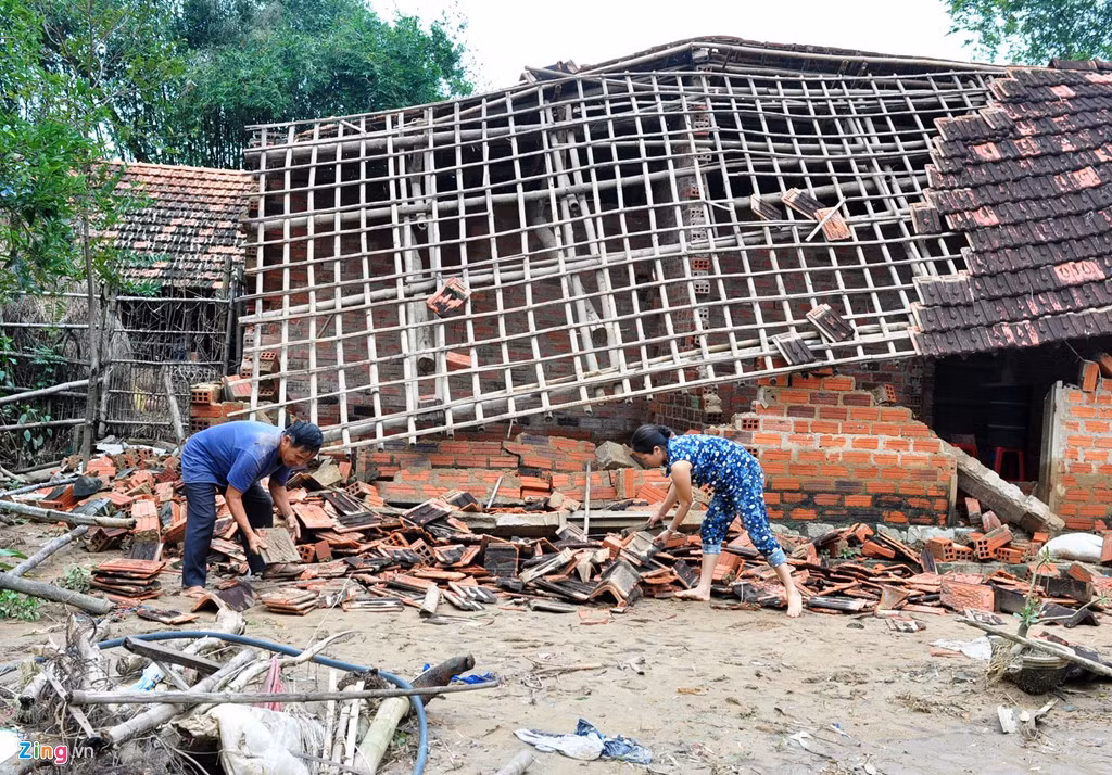 Vợ chồng ông Trần Kim Thành (ngụ thôn Kim Xuyên, xã Phước Hòa) dọn dẹp gạch, ngói vỡ bên căn nhà sập sau mưa lũ.
