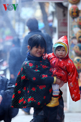 Một bé gái vẹo lưng bế em giúp bố mẹ.