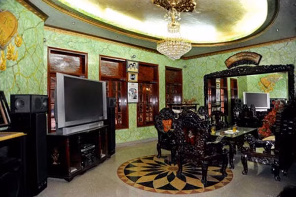 Vào bên trong, phòng khách, màu sơn tường không ăn nhập gì với không gian và bố trí đồ đạc. Chiếc tivi và đèn trần hiện đại có phần hơi "phô" và lệch lạc khi đặt cạnh bộ bàn ghế giả cổ.