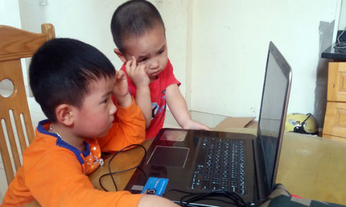 Không ít cha mẹ dỗ con bằng việc cho dùng máy tính, điện thoại. Ảnh: Tùng Anh