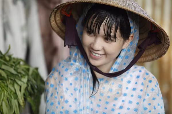 Ngọc Trinh giản dị mặc áo mưa, đội nón lá trong bức ảnh hậu trường phim Vòng eo 56 sắp ra mắt.