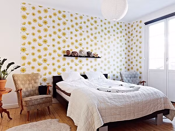 Để không gian nghỉ ngơi thêm mềm mại và cá tính, gia chủ đã chọn lựa giấy dán tường với họa tiết hoa cỏ màu vàng chanh nổi bật để làm đẹp cho bức tường đầu giường ngủ. Thêm những điểm nhấn từ kệ gắn tường và màu của giường để nơi nghỉ ngơi trở nên đẹp ấn tượng hơn.