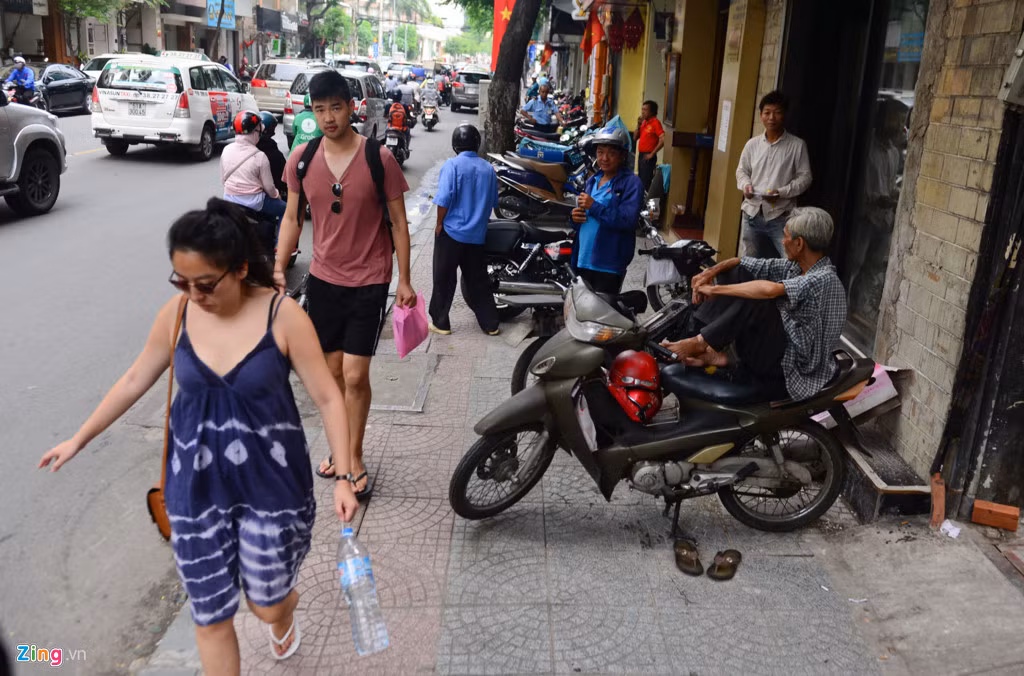 Vỉa hè đường Hai Bà Trưng bị xe máy đậu chiếm hết 2/3, khiến người đi bộ gặp khó khăn khi di chuyển trên vỉa hè.