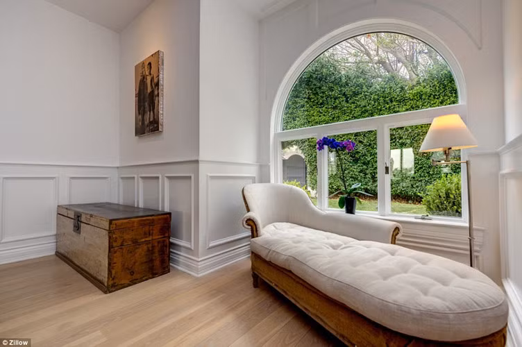 Ngôi nhà chủ yếu có tông màu trắng, nằm gần bãi biển với vườn cây được cắt tỉa cẩn thận.