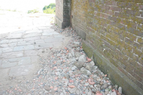 Lối đi qua cổng ngổn ngang nhiều gạch đá rơi do bị xuống cấp.