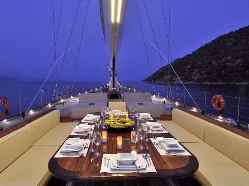 Một bàn ăn đặt trên boong thuyền đủ chỗ cho tất cả hành khách.