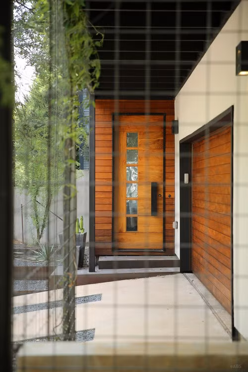 Cánh cửa với chất liệu gỗ và thép kết hợp, bên cạnh đó còn được lắp đặt thêm cả hệ thống khóa công nghệ, lối vào được bố trí ngay bên cạnh nhà để xe.
